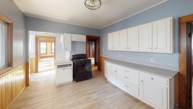 15-17 Brockton Ave, Haverhill, MA 01830 - kitchen with black gas range oven, white cabinetry, light wood-style floors, a wainscoted wall, and light countertops