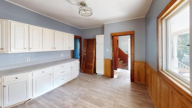 15-17 Brockton Ave, Haverhill, MA 01830 - kitchen featuring a wainscoted wall, light wood finished floors, light countertops, white cabinets, and ornamental molding