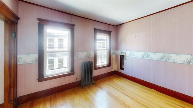 15-17 Brockton Ave, Haverhill, MA 01830 - empty room with radiator heating unit, crown molding, light wood finished floors, wallpapered walls, and a wainscoted wall