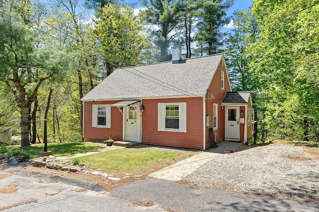 bungalow-style house featuring roof with shingles, a chimney, and a front lawn