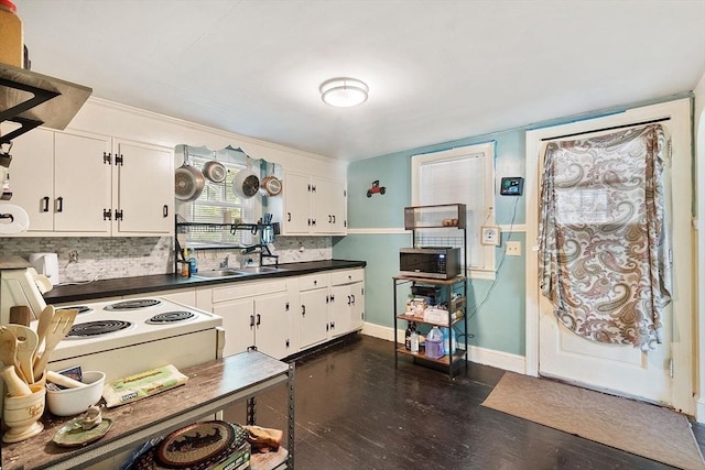 kitchen featuring a sink, backsplash, dark countertops, white cabinets, and dark wood-style floors