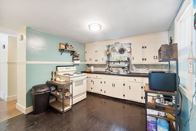 kitchen with electric stove, dark countertops, dark wood-style floors, decorative backsplash, and white cabinets