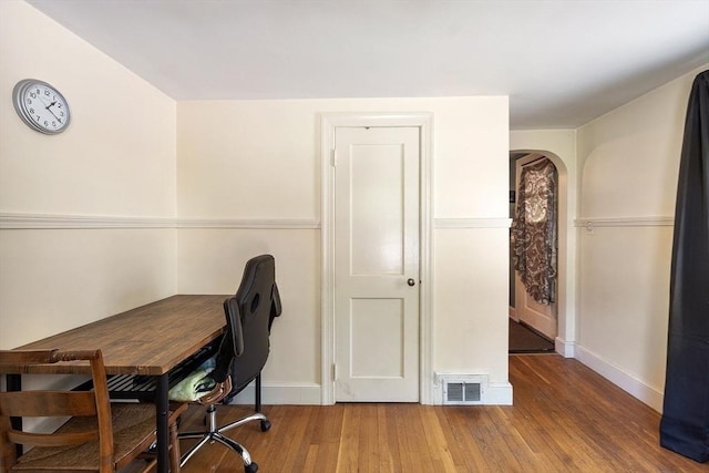 home office with arched walkways, wood finished floors, and baseboards