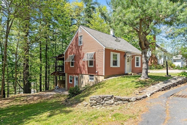 view of home's exterior with a yard, a deck, and a shingled roof
