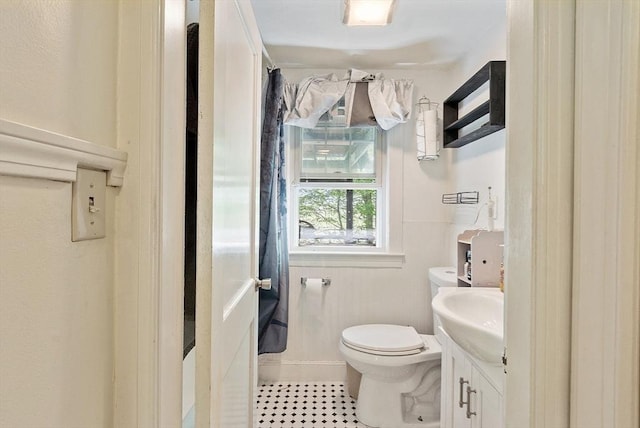 bathroom with toilet, vanity, tile patterned flooring, and baseboards