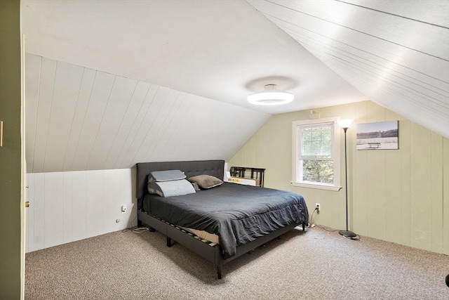 bedroom featuring carpet floors, wood walls, and vaulted ceiling