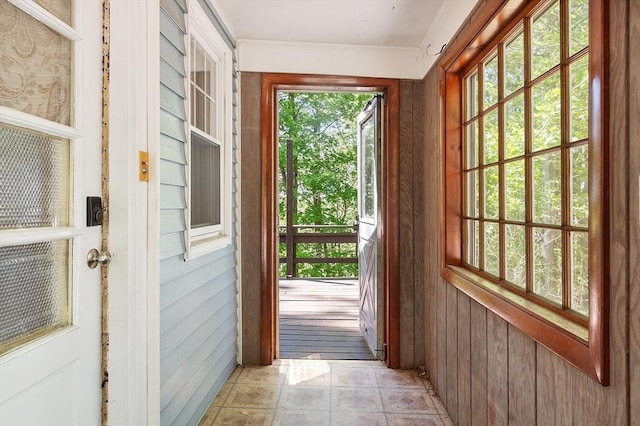 doorway featuring crown molding and wood walls