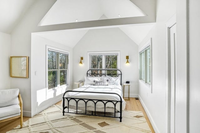 bedroom with vaulted ceiling with beams, light hardwood / wood-style floors, and multiple windows