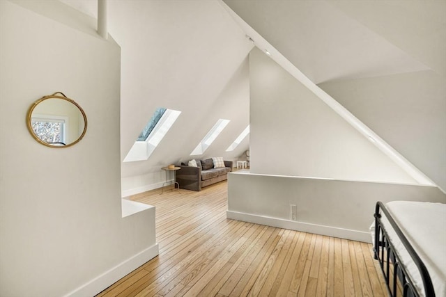 additional living space featuring a skylight and light hardwood / wood-style flooring