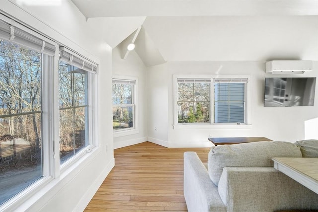 interior space featuring vaulted ceiling, light wood-type flooring, and a wall mounted AC