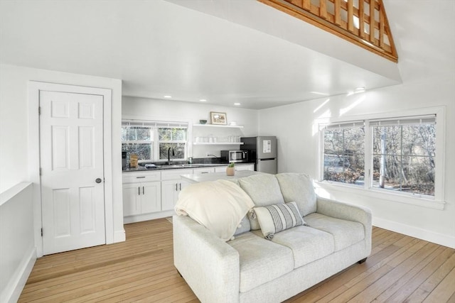 living room featuring a wealth of natural light, sink, and light hardwood / wood-style floors