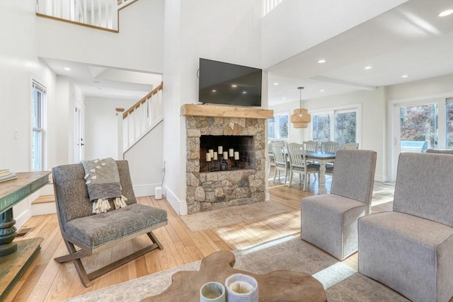 living room featuring a fireplace, a high ceiling, and light wood-type flooring