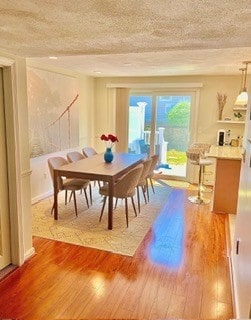 dining space featuring a textured ceiling and hardwood / wood-style floors