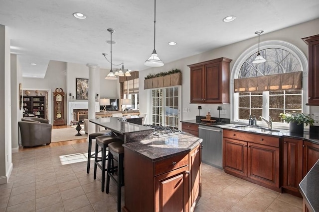 kitchen featuring a kitchen bar, sink, decorative light fixtures, a center island, and appliances with stainless steel finishes