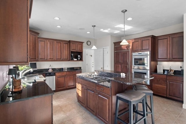 kitchen with sink, hanging light fixtures, a kitchen island, dark stone counters, and stainless steel double oven