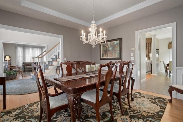 dining space featuring hardwood / wood-style flooring, ornamental molding, a raised ceiling, and a chandelier