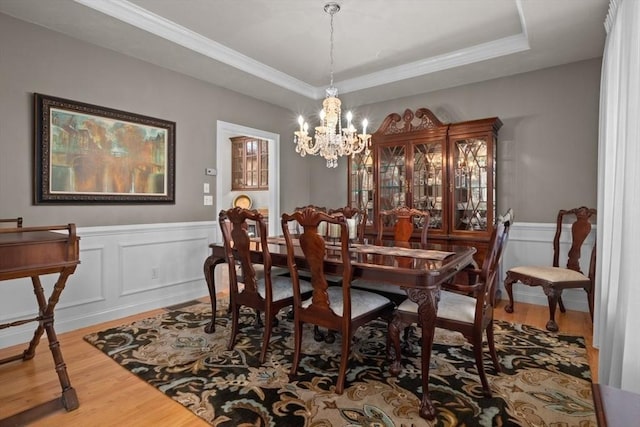 dining space featuring hardwood / wood-style flooring, ornamental molding, a notable chandelier, and a tray ceiling