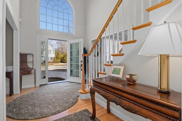 foyer entrance with a towering ceiling and light hardwood / wood-style flooring