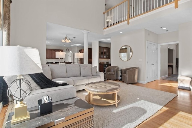 living room featuring ornate columns, a towering ceiling, and light hardwood / wood-style floors