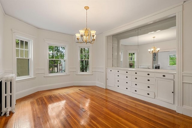 179 Rawson Unit 2, Brookline, MA 02445 - unfurnished dining area with a chandelier, radiator, light wood-style floors, plenty of natural light, and a decorative wall