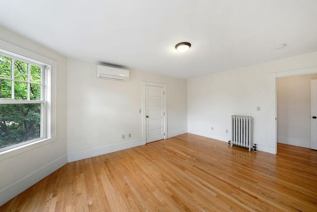 179 Rawson Unit 2, Brookline, MA 02445 - spare room featuring radiator, a wall mounted AC, light wood-style floors, baseboards, and a smoke detector