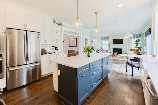 kitchen featuring dark wood-type flooring, appliances with stainless steel finishes, white cabinets, and a fireplace