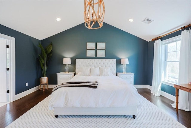 bedroom featuring visible vents, an inviting chandelier, wood finished floors, baseboards, and vaulted ceiling