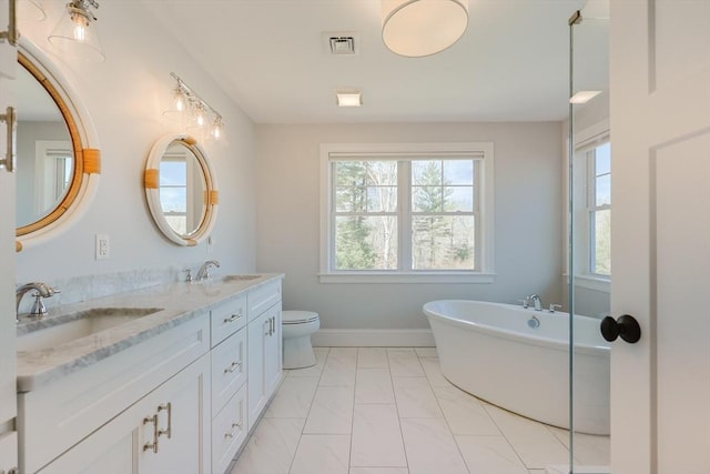 full bath with a sink, double vanity, marble finish floor, a freestanding tub, and visible vents