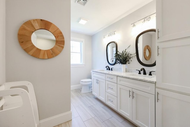 full bath with a sink, double vanity, toilet, baseboards, and visible vents