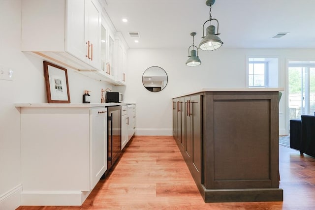 kitchen with visible vents, white cabinetry, a peninsula, and baseboards