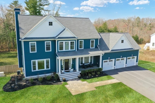 view of front of house with a garage, aphalt driveway, a front yard, a chimney, and a porch