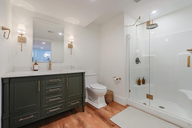 bathroom with a shower stall, wood finished floors, vanity, baseboards, and toilet