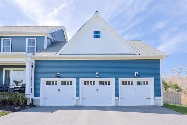 view of front of home featuring fence, roof with shingles, aphalt driveway, a garage, and board and batten siding