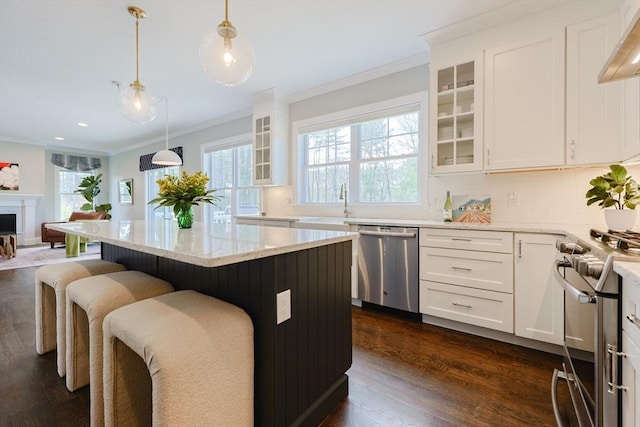 kitchen featuring crown molding, extractor fan, appliances with stainless steel finishes, and a breakfast bar area