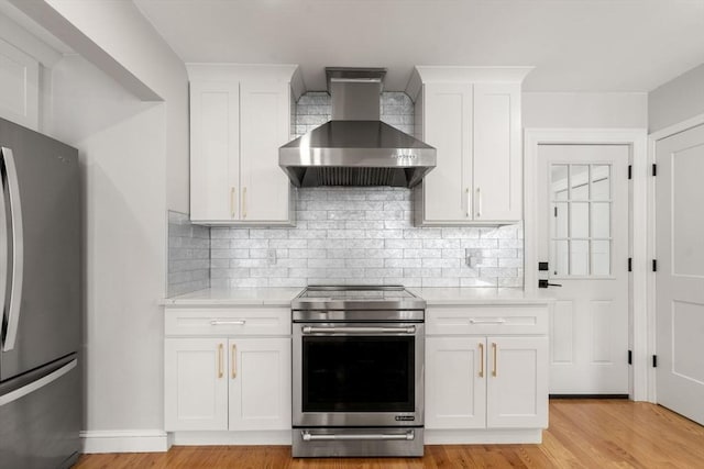 kitchen with light countertops, wall chimney exhaust hood, stainless steel appliances, white cabinetry, and decorative backsplash