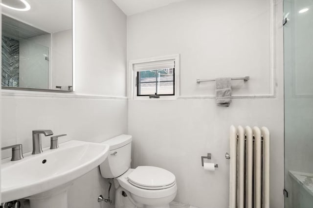 bathroom featuring an enclosed shower, toilet, a sink, and radiator heating unit