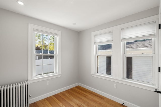 unfurnished room featuring baseboards, light wood-style flooring, radiator, and recessed lighting