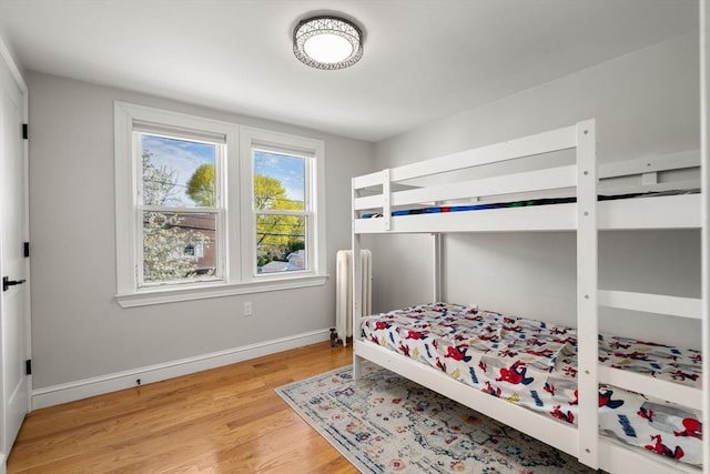 bedroom featuring radiator, baseboards, and light wood finished floors