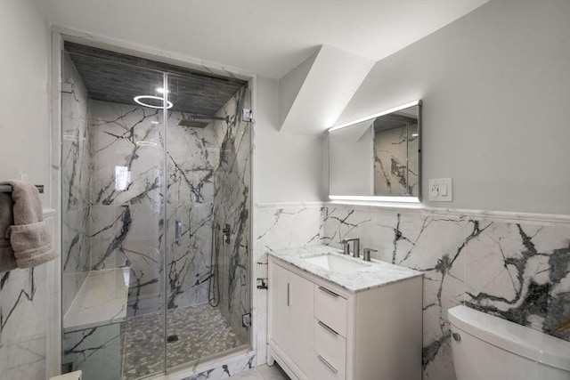 bathroom with tile walls, vanity, toilet, marble finish floor, and a marble finish shower