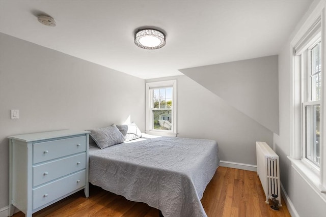 bedroom with baseboards, radiator heating unit, and wood finished floors