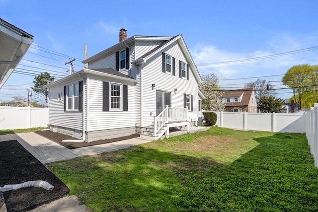 rear view of property featuring a fenced backyard, a chimney, and a yard