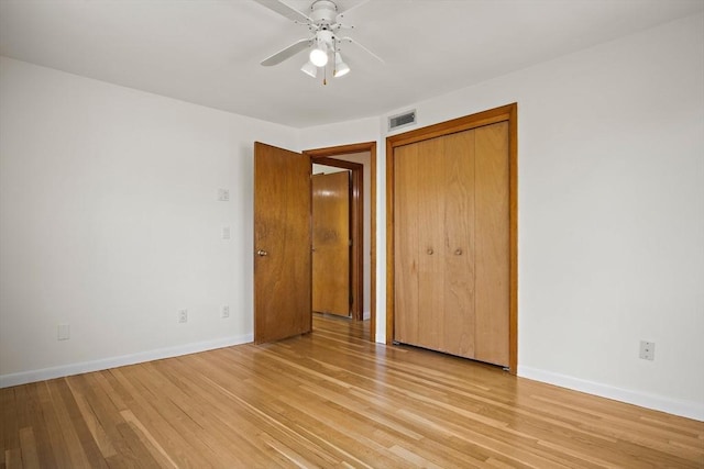 unfurnished bedroom featuring baseboards, a closet, visible vents, and light wood-style floors