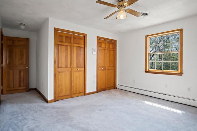 unfurnished bedroom featuring multiple closets, a baseboard radiator, light carpet, ceiling fan, and baseboards