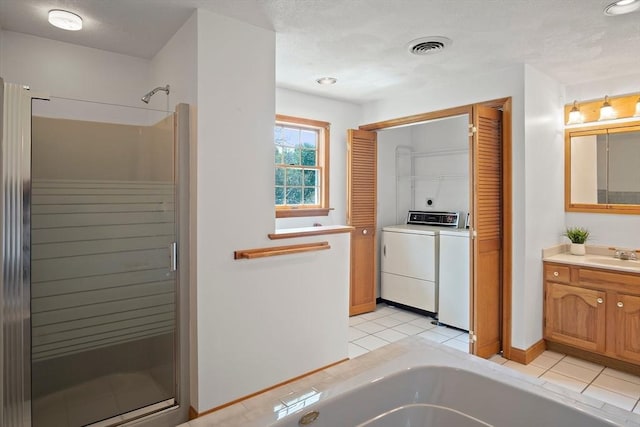 bathroom featuring washer and dryer, a stall shower, a tub to relax in, tile patterned floors, and vanity