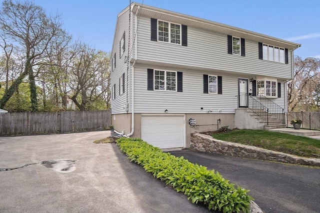 colonial-style house with fence, an attached garage, and driveway