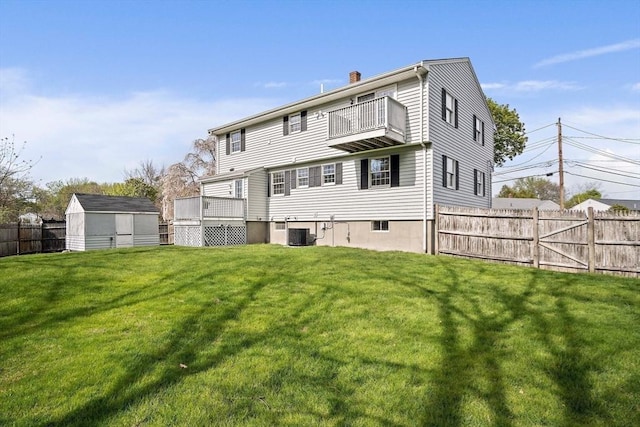 rear view of house featuring a yard, a chimney, a fenced backyard, and a balcony
