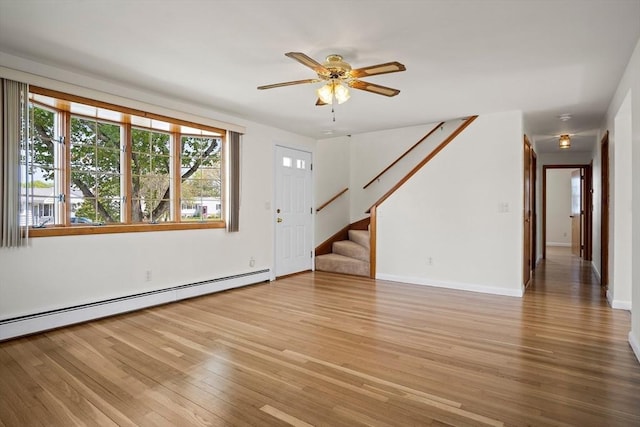 unfurnished living room featuring wood finished floors, a ceiling fan, baseboards, a baseboard heating unit, and stairs