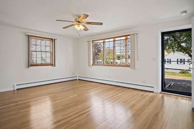 unfurnished room with a baseboard radiator, hardwood / wood-style floors, and a healthy amount of sunlight