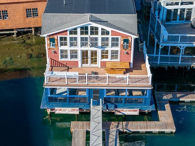 back of property with roof with shingles and a water view