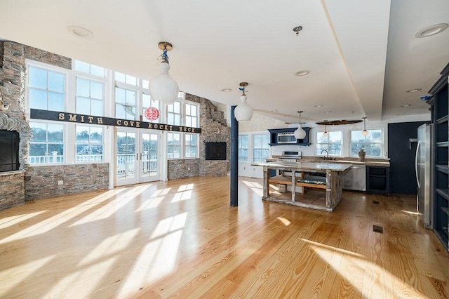 interior space with a fireplace, open floor plan, an island with sink, stainless steel appliances, and a sink